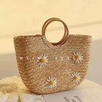 Bolsa artesanal de palha premium Lavinni Margarida Bali com aplicações florais e alças circulares de madeira sob luz natural.