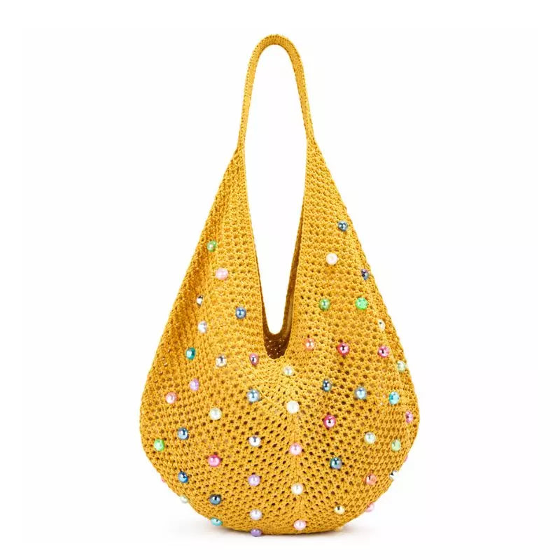 Bolsa de crochê Lavinni Capri Pearl na cor amarela com formato balde e aplicações de pérolas coloridas brilhantes em fundo branco.