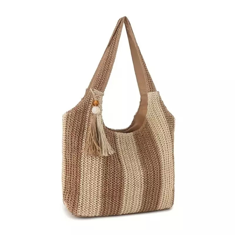 Visão em ângulo da bolsa de crochê Lavinni Sunset Stripes destacando a largura da base, o pingente de franja e as listras em degradê.