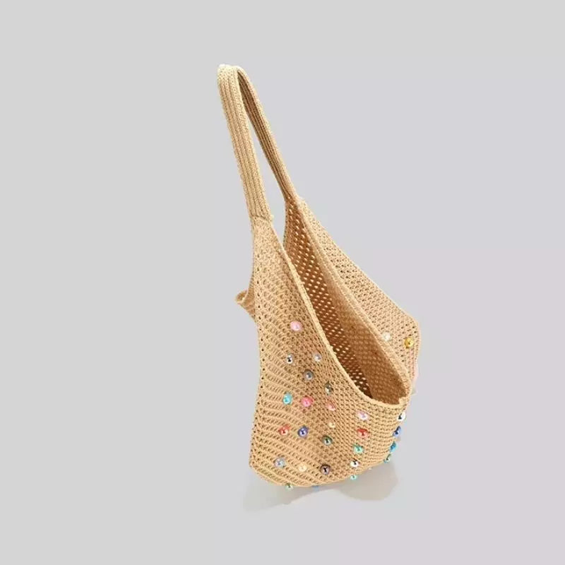 Visão de perfil e abertura da bolsa de praia chique Lavinni Capri Pearl na cor cáqui, destacando o caimento vertical da alça e as contas coloridas.